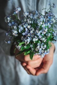 ragazza giovane che tiene un bouquet di non ti scordar di me. Fiori celesti. Foto sfocata ai lati.