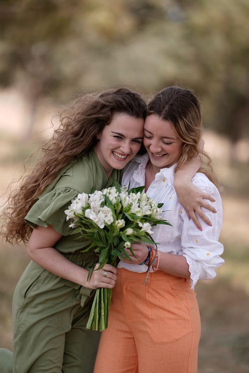 ragazze sorridenti con mazzo di fiori bianchi